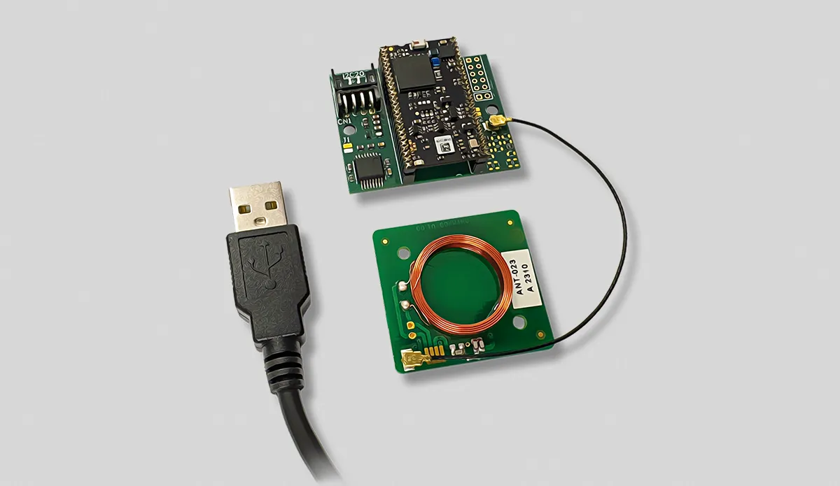 Green circuit boards with electronic components and a black USB connector cable on a gray background.