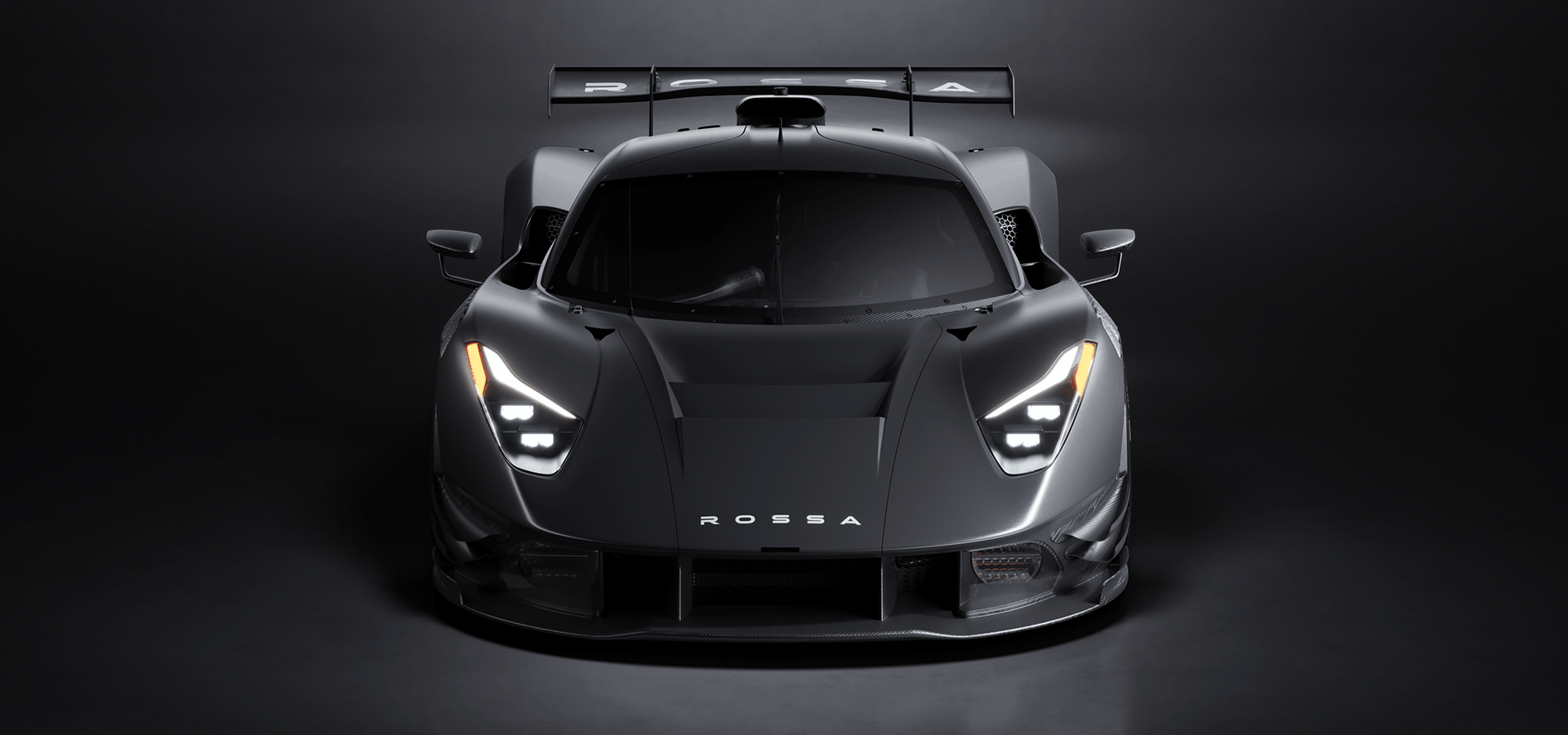 Front view of a black Rossa hypercar with illuminated headlights and a large rear wing against a dark background.