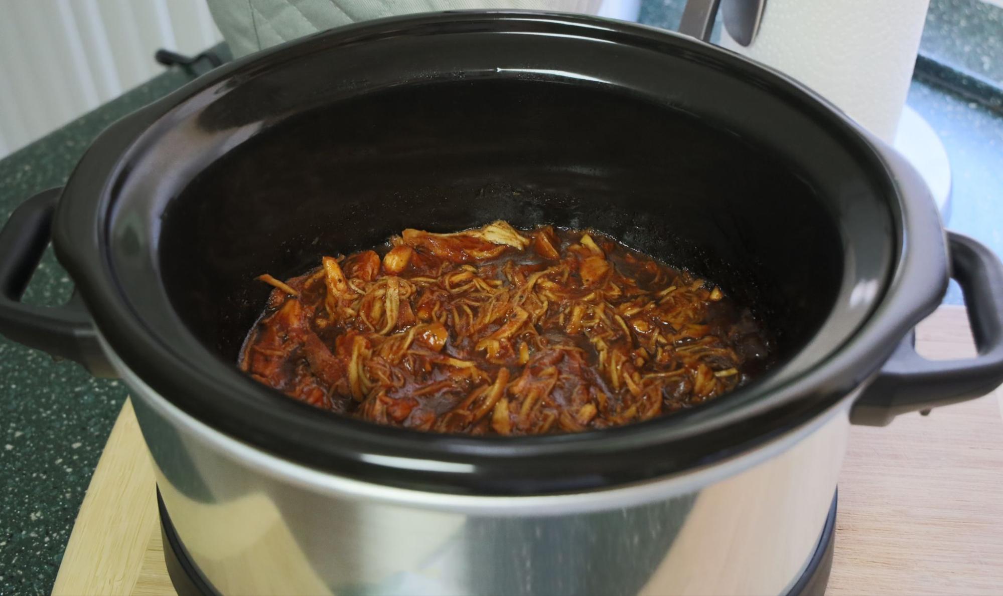 Top view of the inside of a slow cooker with pulled pork inside