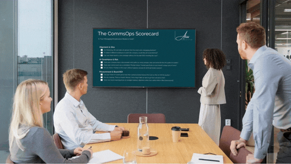 Four professionals in a meeting room looking at a screen showing The CommsOps Scorecard with metrics and criteria.