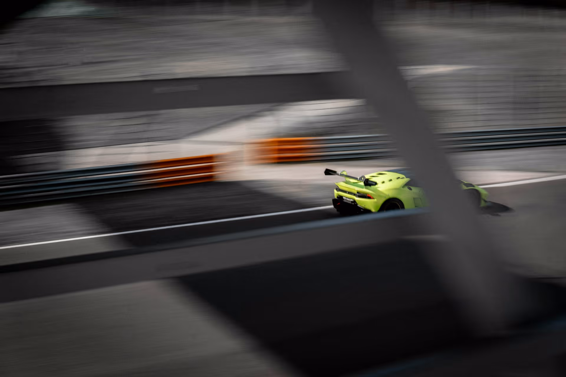 Bright yellow sports car speeding on a racetrack with blurred surroundings.