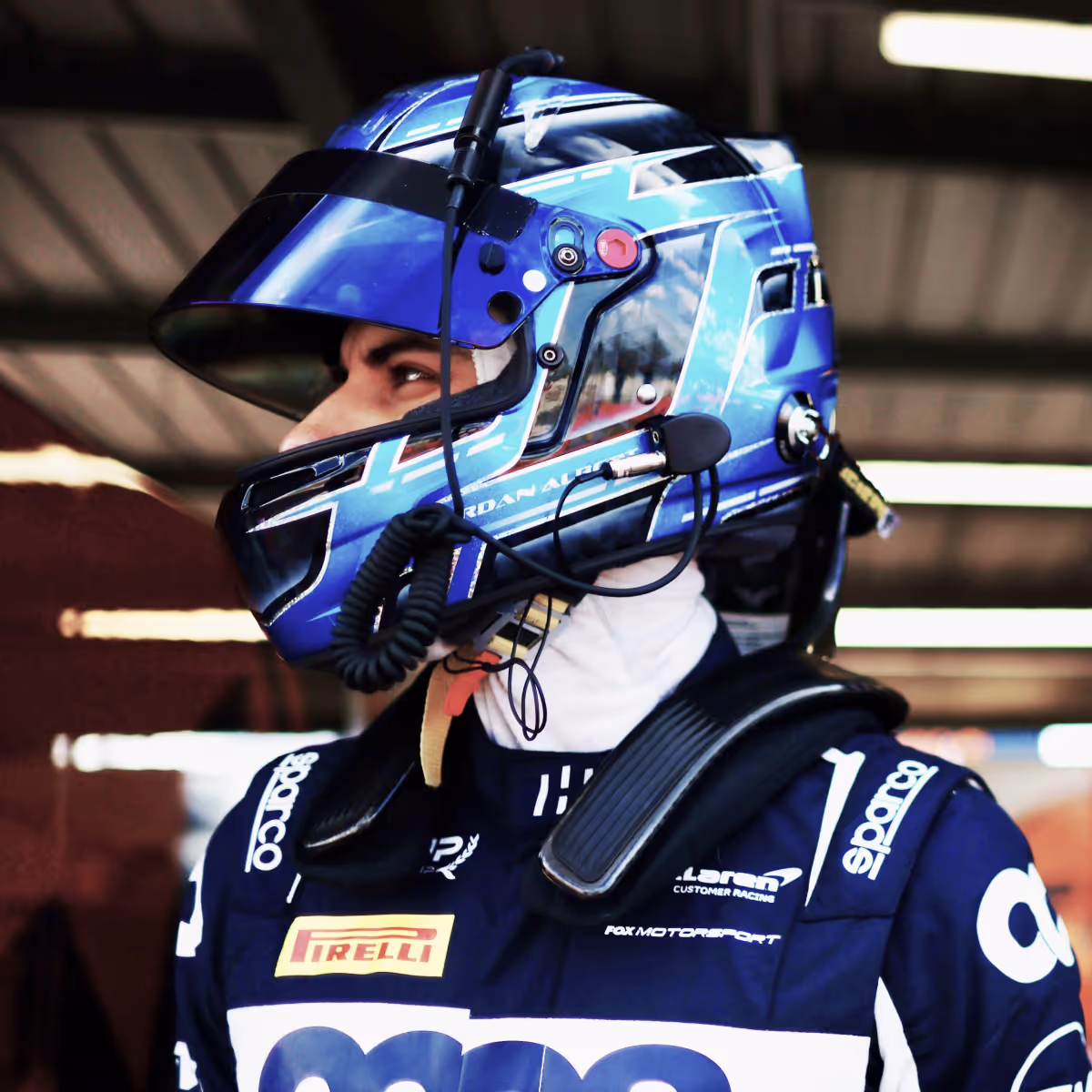Jordan Albert wearing a blue helmet and racing suit with Pirelli and Sparco logos.