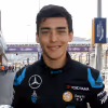 Matt Solo - Smiling young man in a black racing suit with Mercedes and other sponsor logos, standing outdoors near a racetrack.