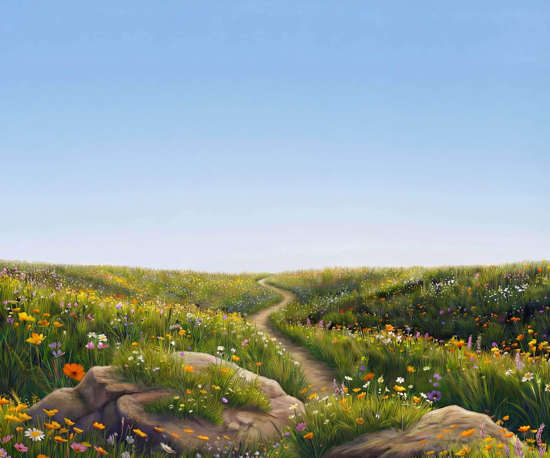 Green meadow with colorful wildflowers in front of distant blue-green mountains under a clear blue sky.