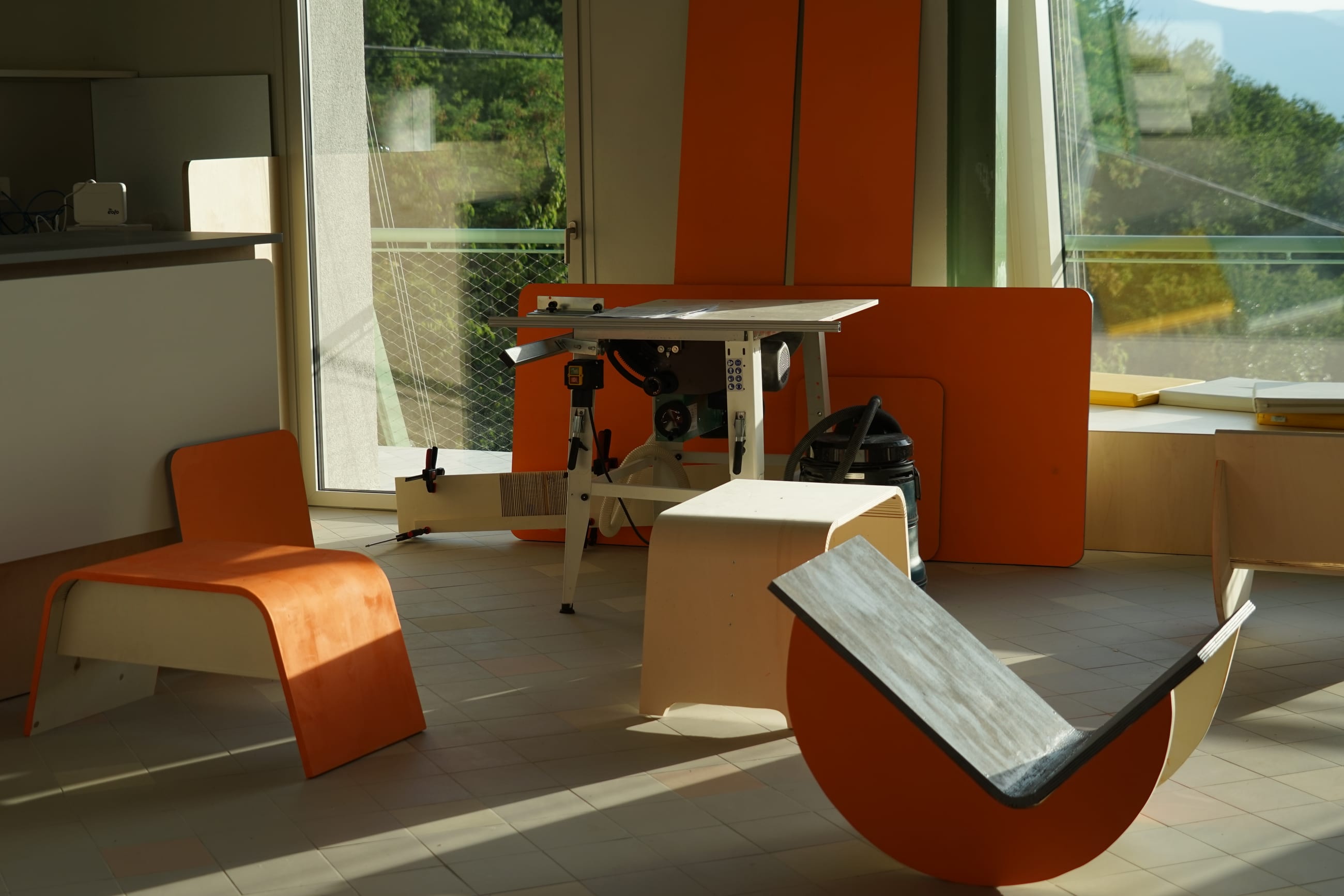Arredi in legno arancione in uno spazio interno luminoso, accanto ad attrezzi da laboratorio