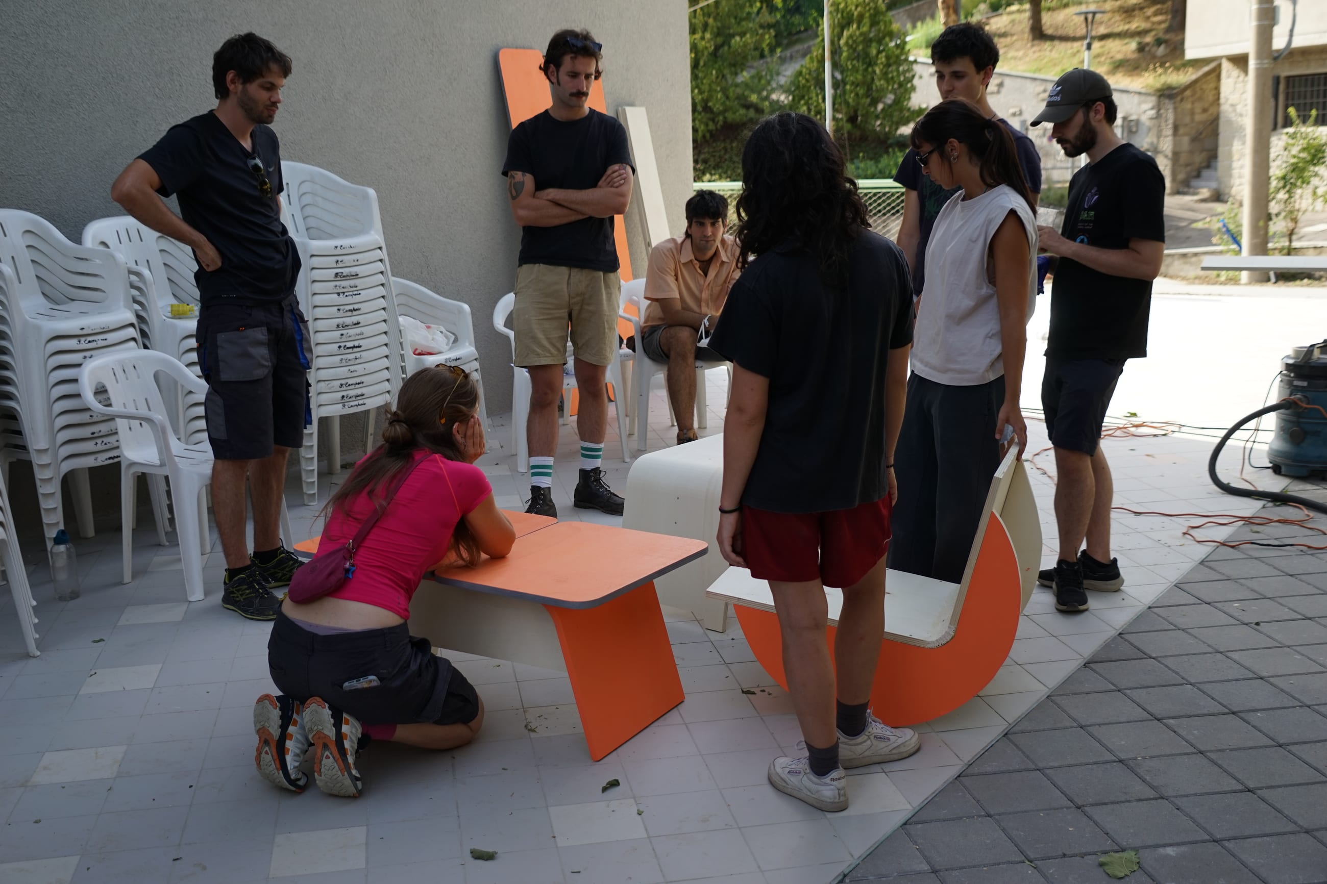 Persone attorno a sedute e tavolini in legno curvato arancione su una terrazza