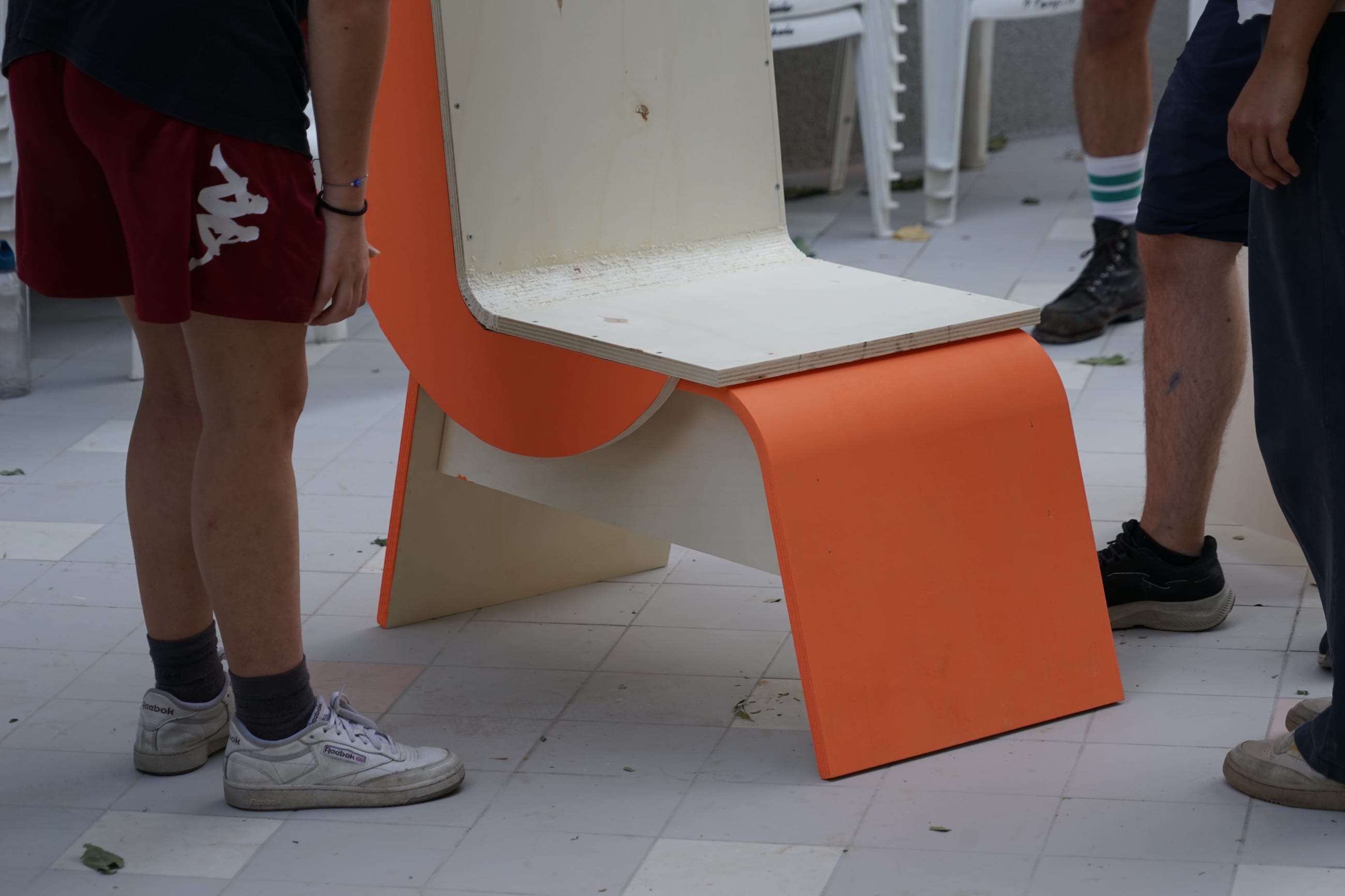 Seduta in legno curvato con fianchi arancioni appoggiata su una terrazza