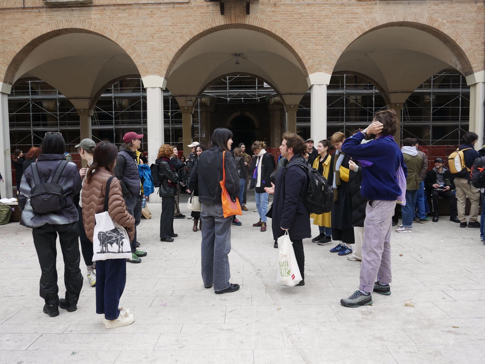 Gruppo di persone raccolto in un cortile con portico ad archi