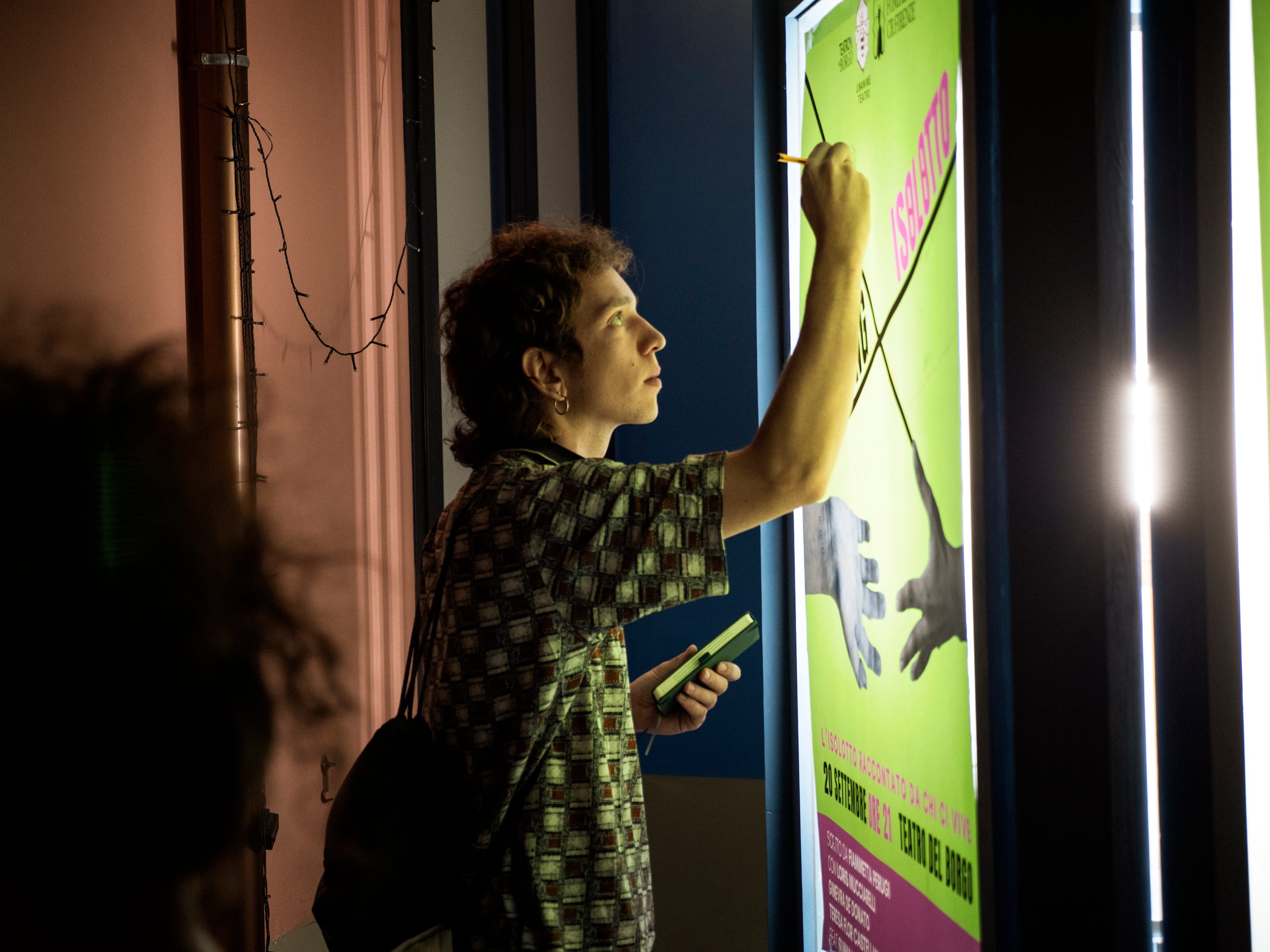 Persona che scrive con una matita su un grande poster verde illuminato