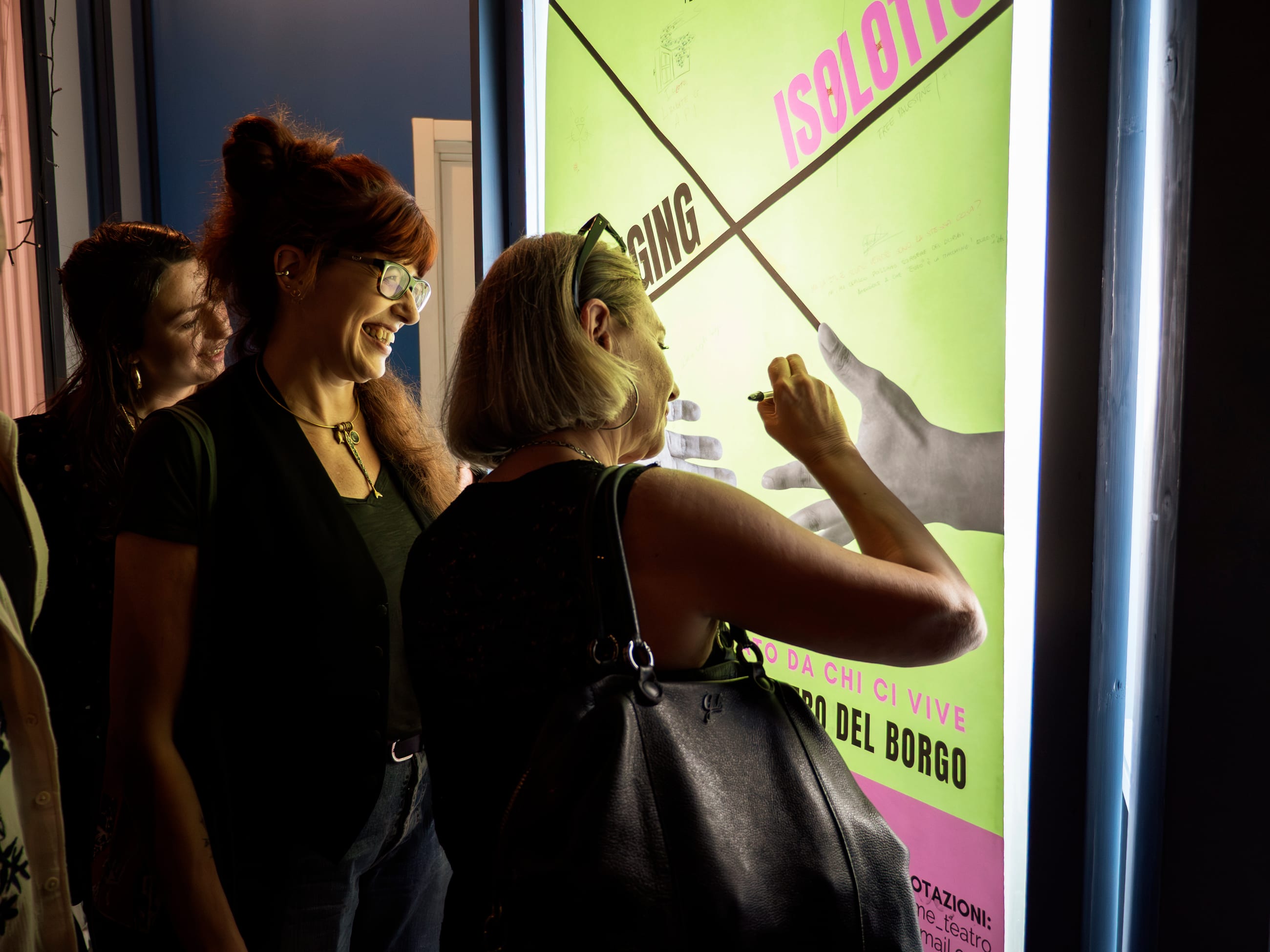 Due persone sorridenti lasciano un segno sul poster luminoso verde