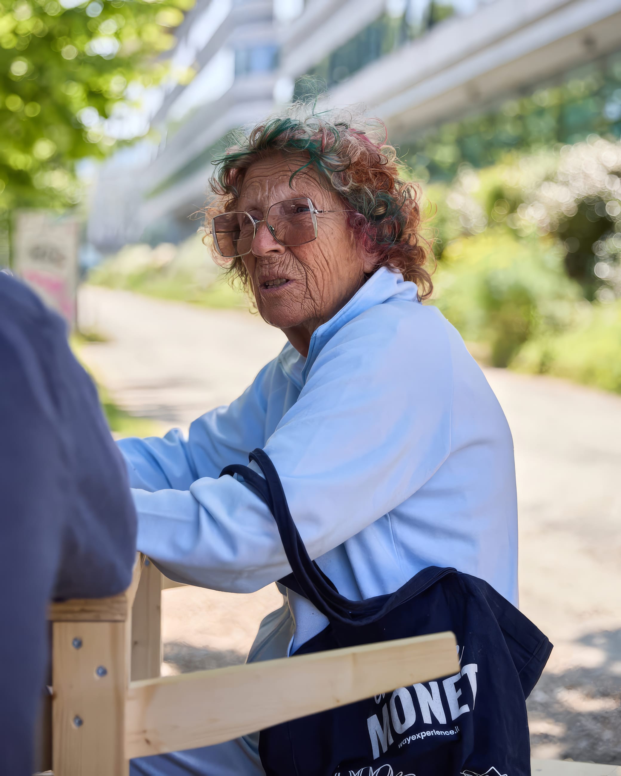 Persona seduta a un tavolo in legno all'aperto, in ascolto durante una conversazione