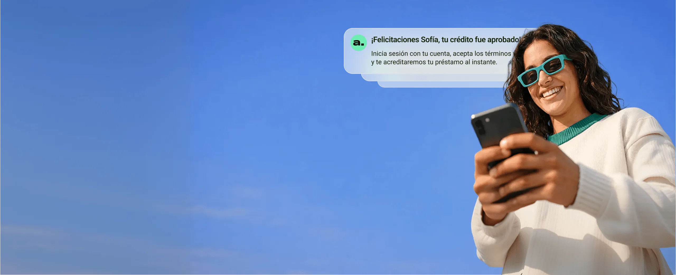 Mujer sonriente con gafas de sol verdes sosteniendo un teléfono móvil bajo un cielo azul, con un mensaje que confirma la aprobación de su crédito.