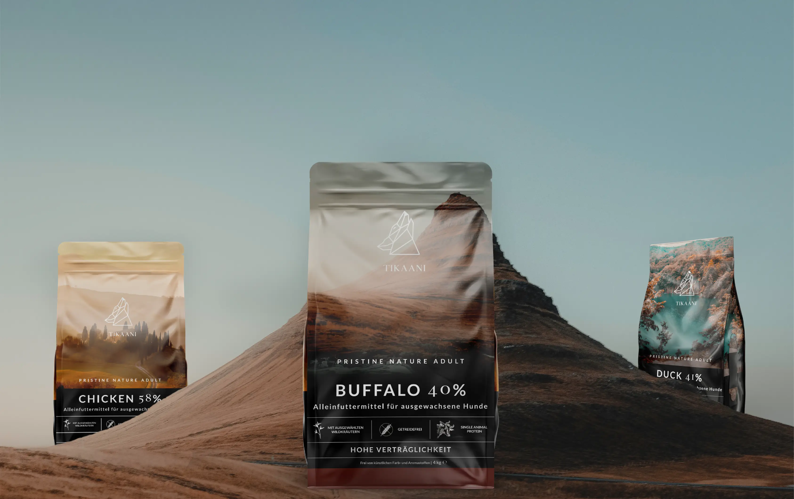 Three Tikaani dog food bags labeled Chicken 58%, Buffalo 40%, and Duck 41% on a mountainous background.