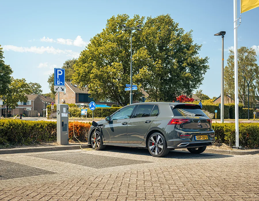 Elektrische auto die oplaadt bij een laadpaal op de parkeerplaats van Winkelcentrum Hasselo op een zonnige dag