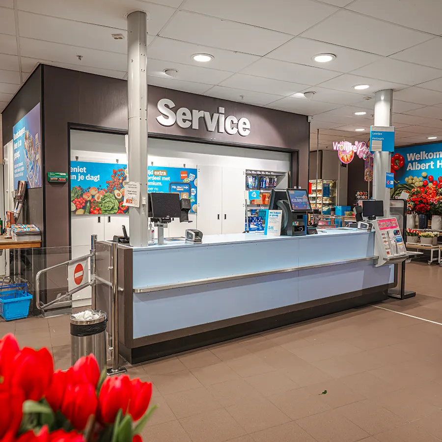 Servicebalie van Albert Heijn met rode tulpen op de voorgrond