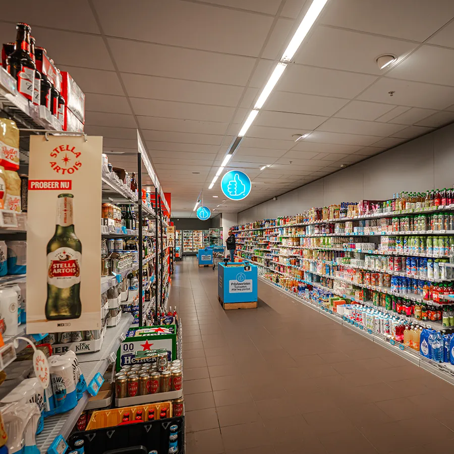 Lange gangpaden met dranken bij Albert Heijn, waaronder bier en frisdrank