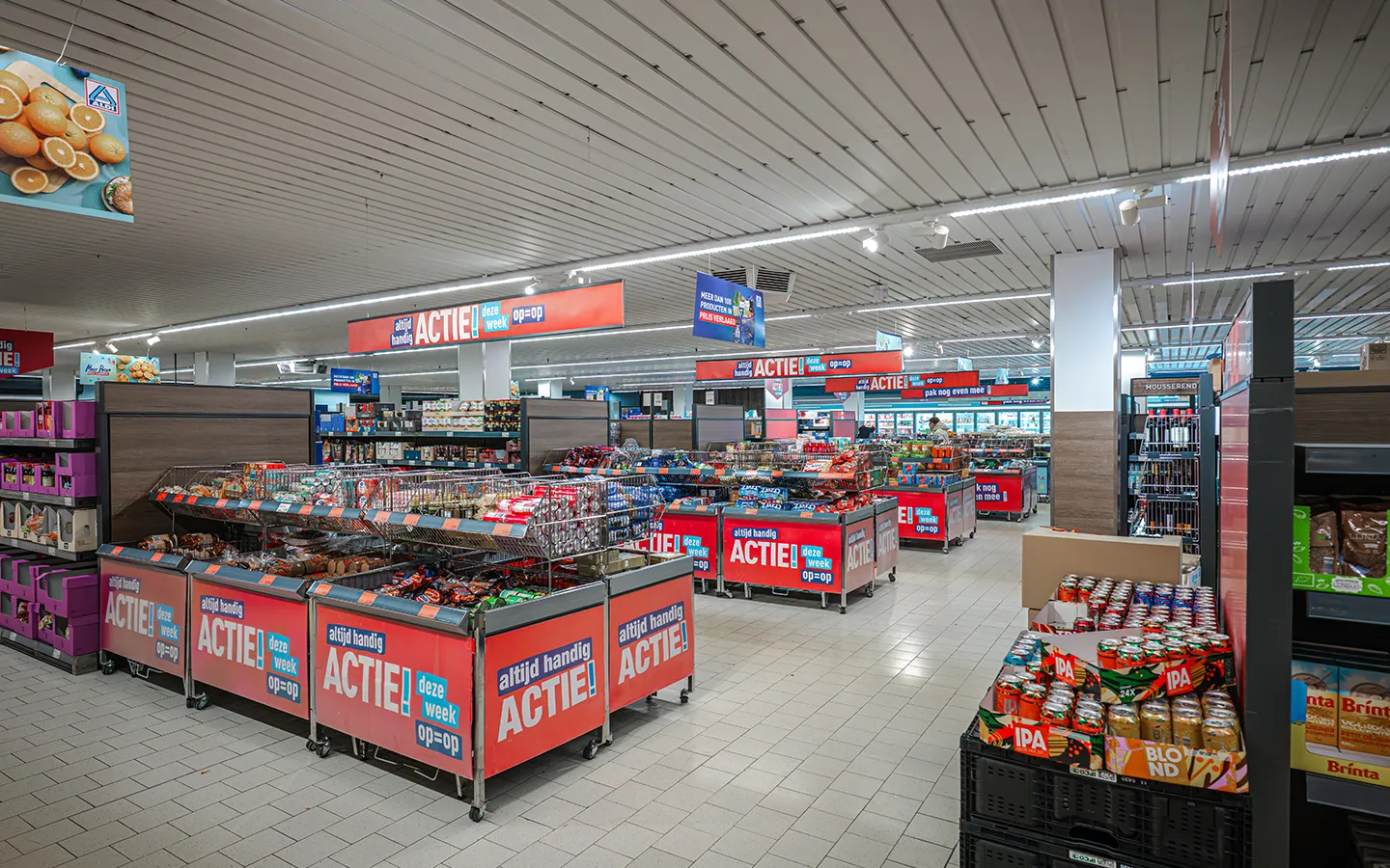 Winkelinterieur van Aldi met meerdere 'Altijd Handig Actie' displays en aanbiedingsbakken