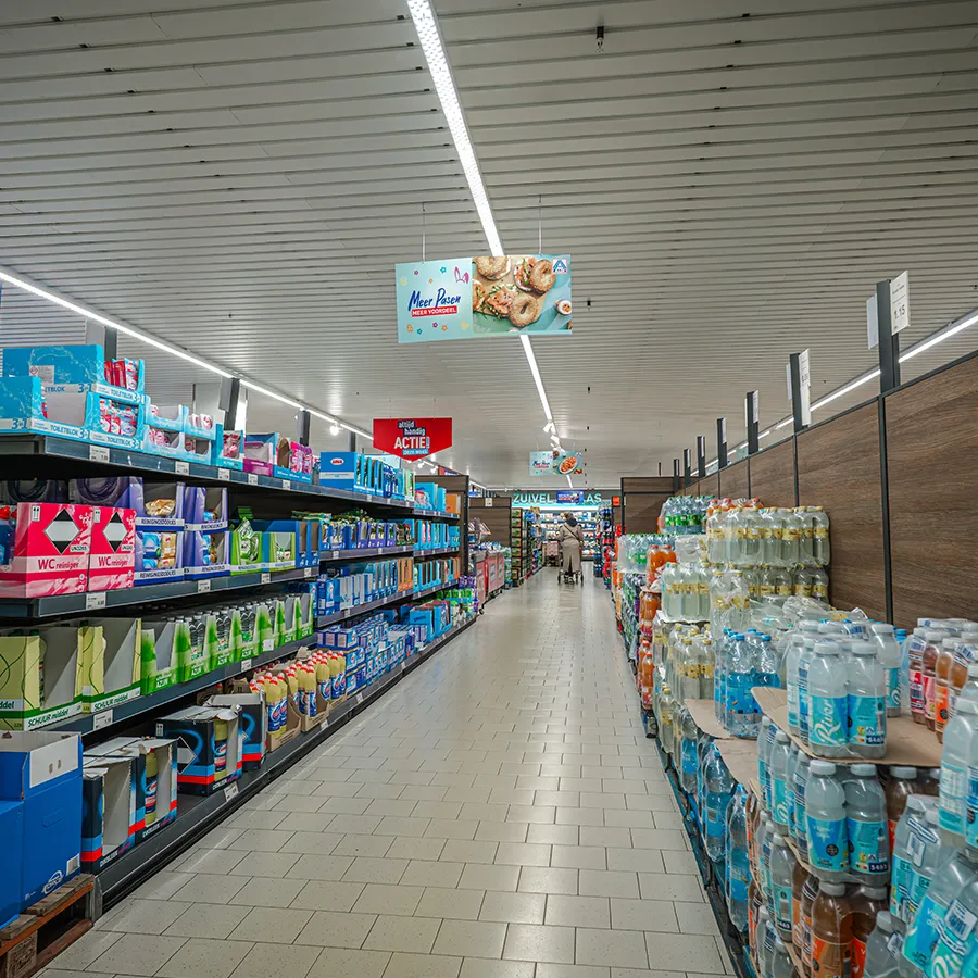 Gangpad bij Aldi met reinigingsproducten en waterflessen, met Pasen-actie display aan het plafond