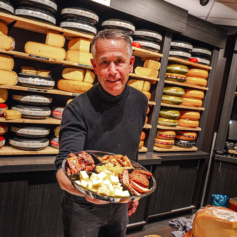 Medewerker van Patrick’s in Winkelcentrum Hasselo presenteert een schaal met kaas en hapjes