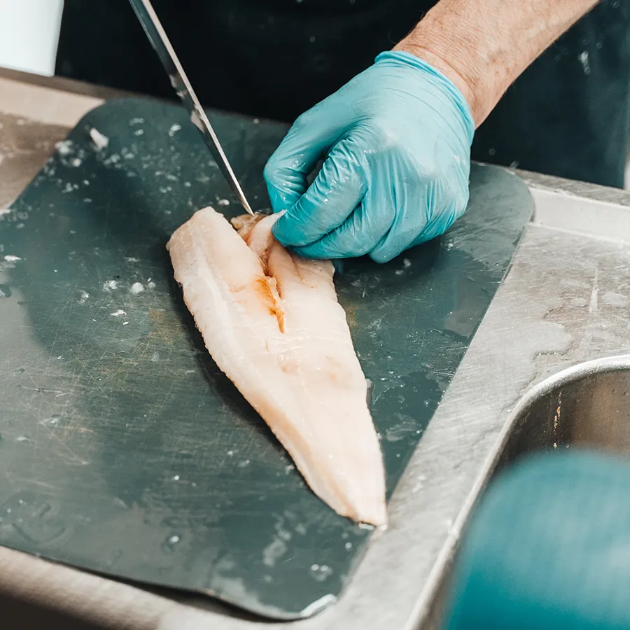 Medewerker snijdt verse visfilet bij visspeciaalzaak De Frens