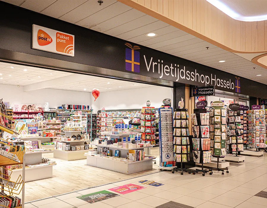 Gevel en ingang van Vrijetijdsshop Hasselo met kaarten en cadeaus