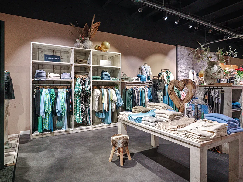 Afdeling dameskleding bij ÉlégAnT Mode in Winkelcentrum Hasselo met kleurrijke kledingrekken, gevouwen items en decoratieve vazen
