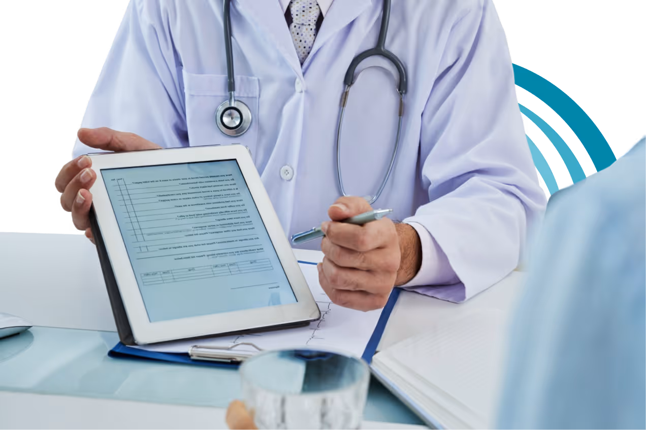 Doctor in white coat with stethoscope showing medical information on a tablet to a patient.