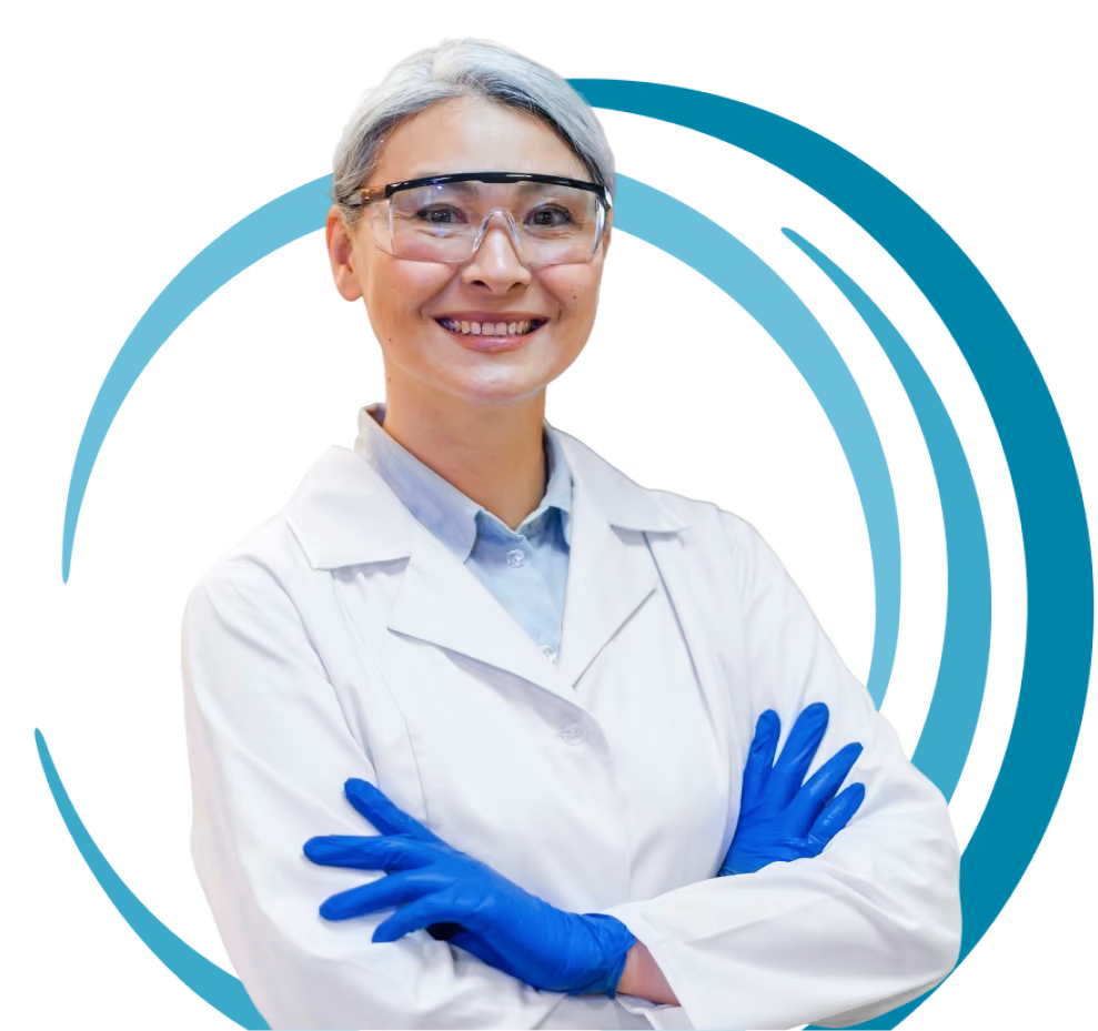 Smiling scientist with gray hair wearing a lab coat, blue gloves, and safety goggles.
