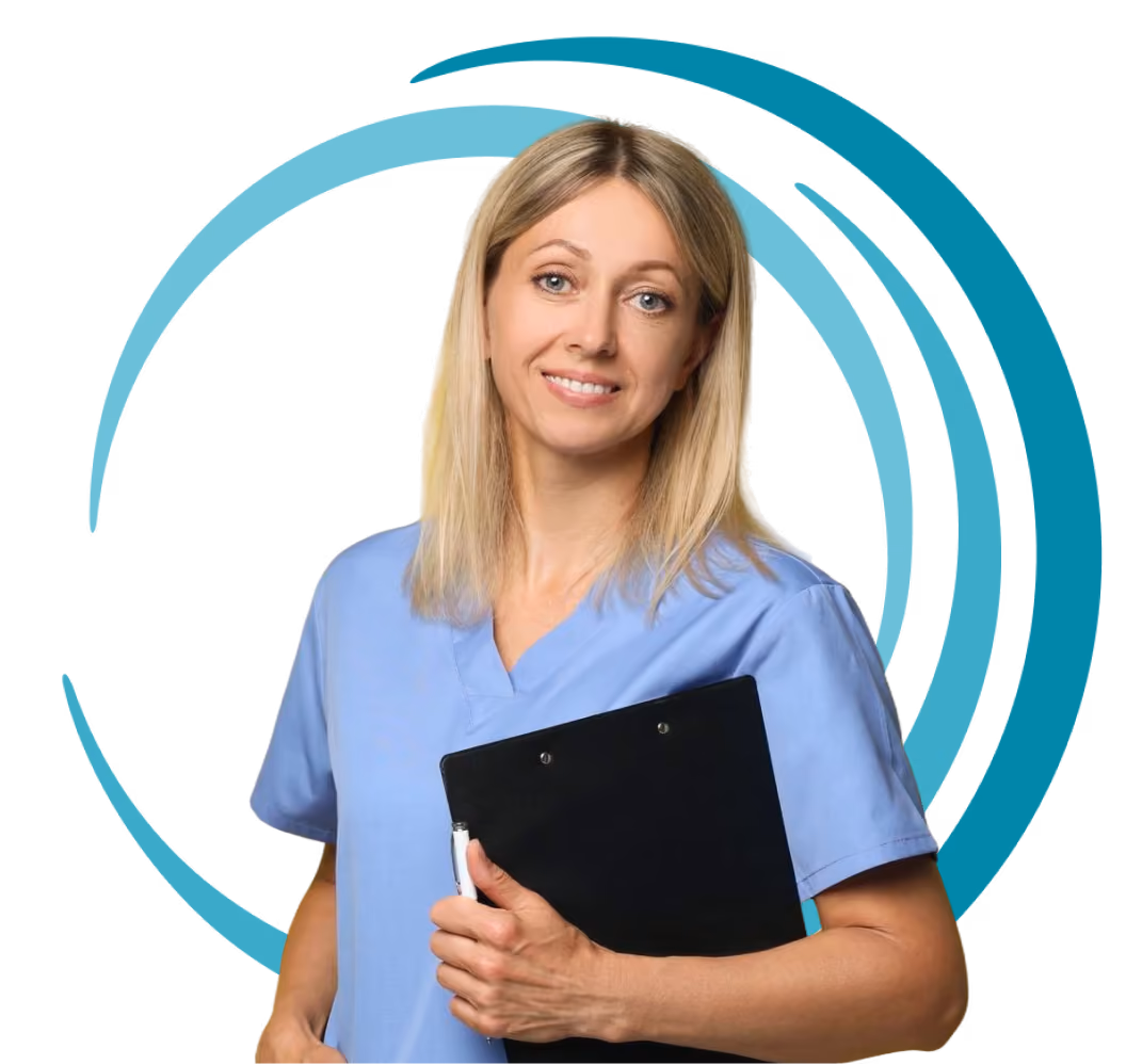 Smiling female healthcare worker in blue scrubs holding a black clipboard with pen.