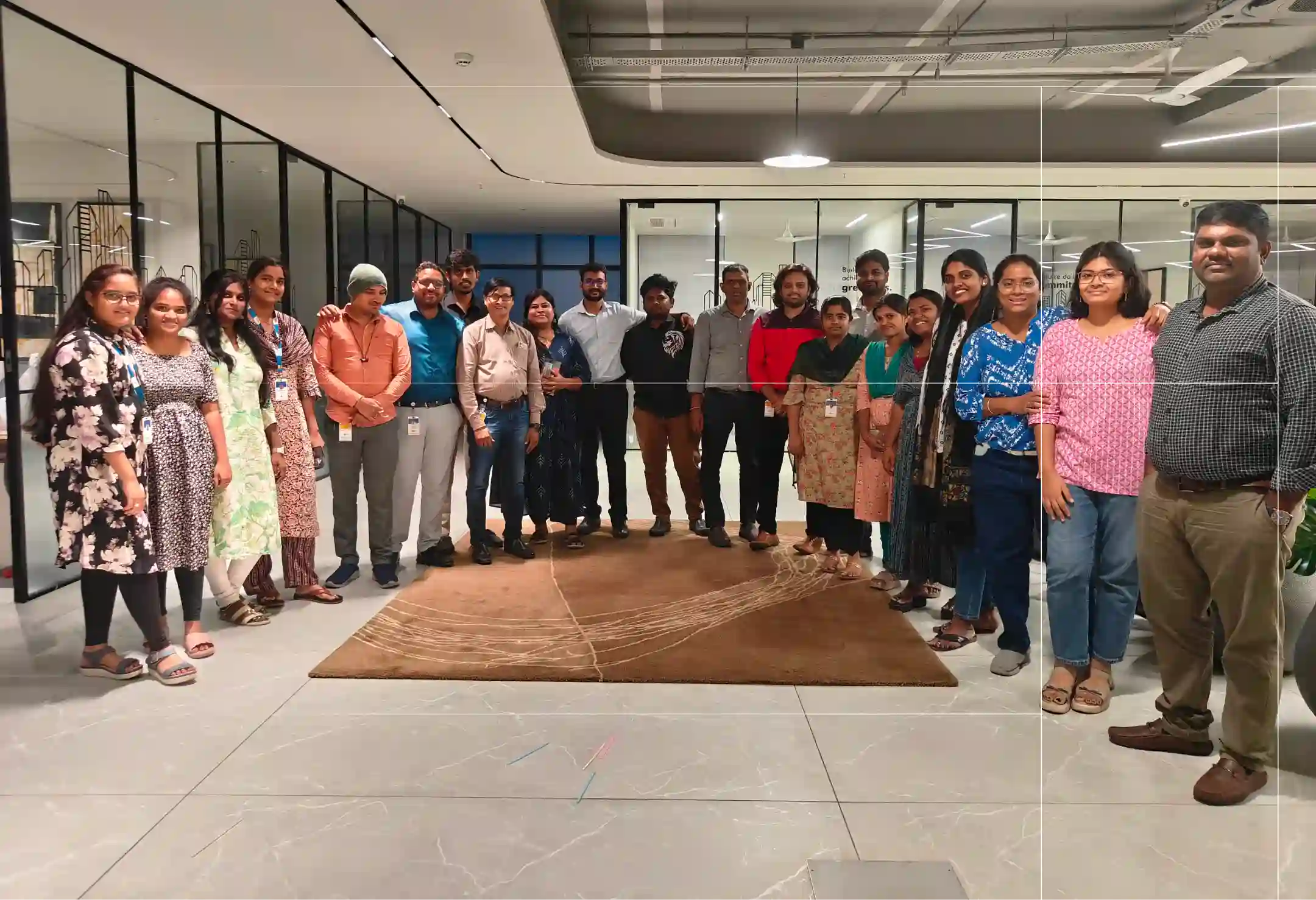 Group of diverse colleagues standing together inside a modern office space with glass walls.
