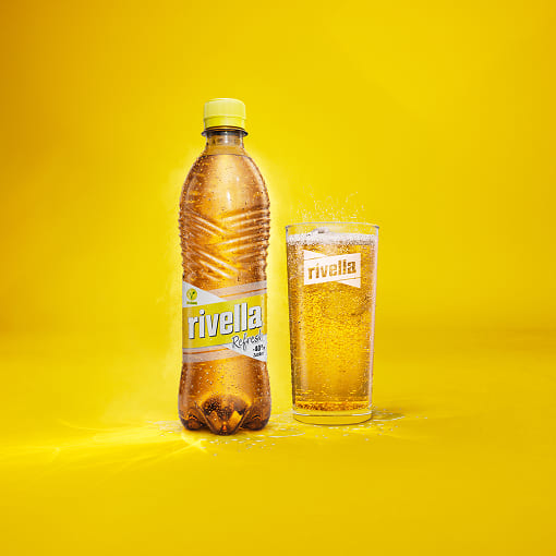 Rivella Gelb Flasche und gefülltes Glas auf gelbem Hintergrund