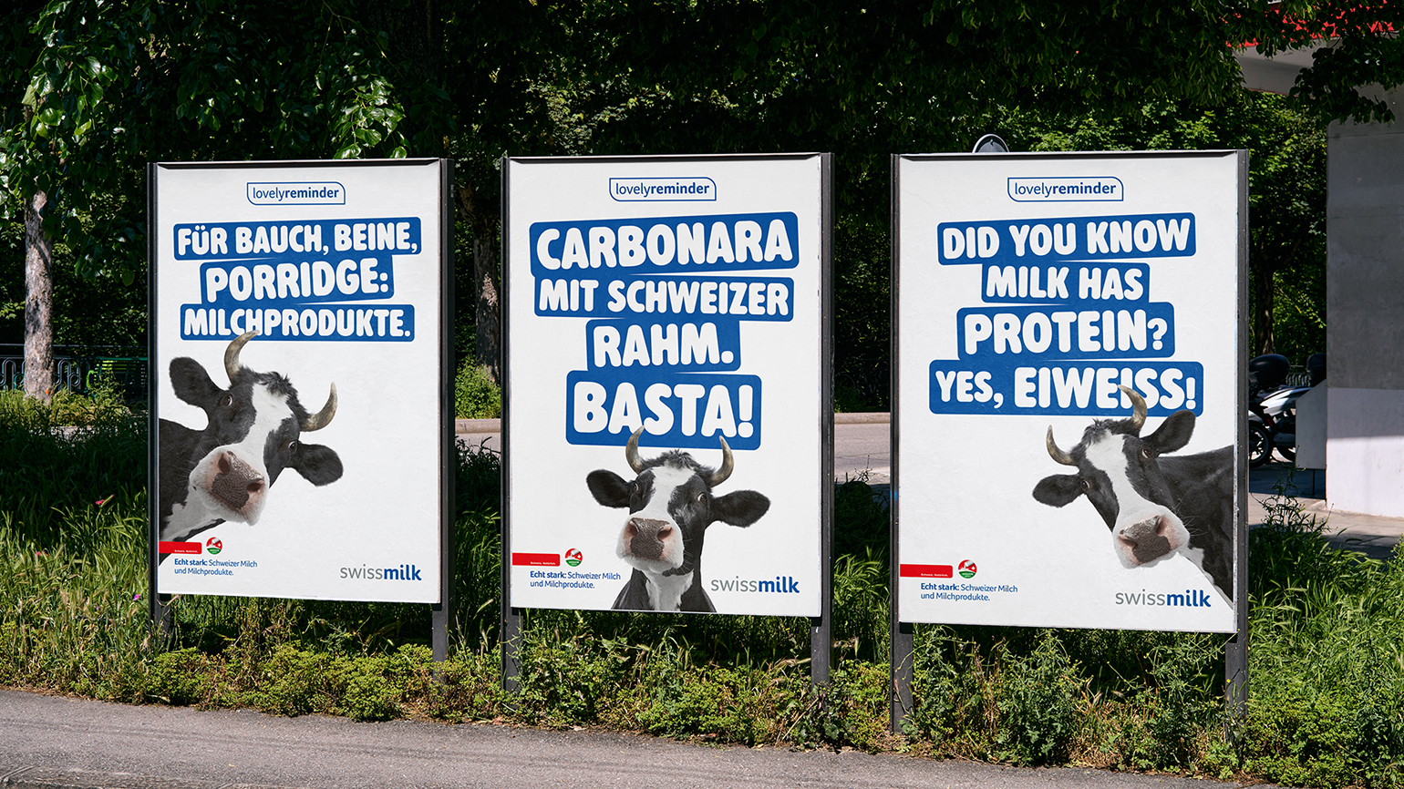 Drei Swissmilk-Plakate der Kampagne «Lovely Reminder» an einer Strasse, mit Lovely der Kuh und Sprüchen zu Milchprodukten