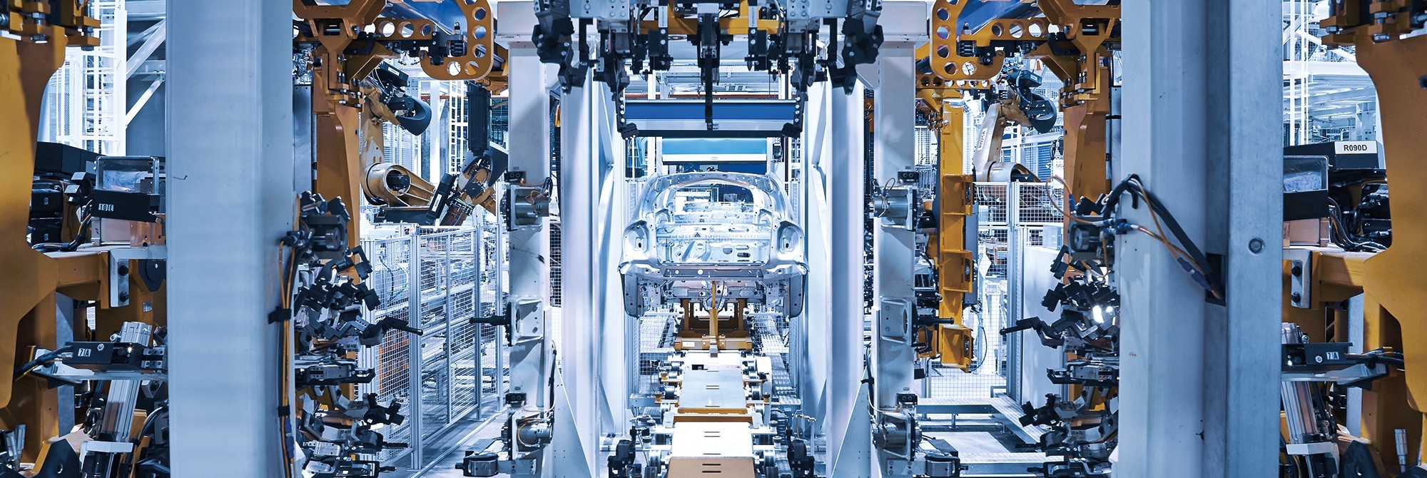 Automated robotic assembly line with car frame positioned in the center for manufacturing.
