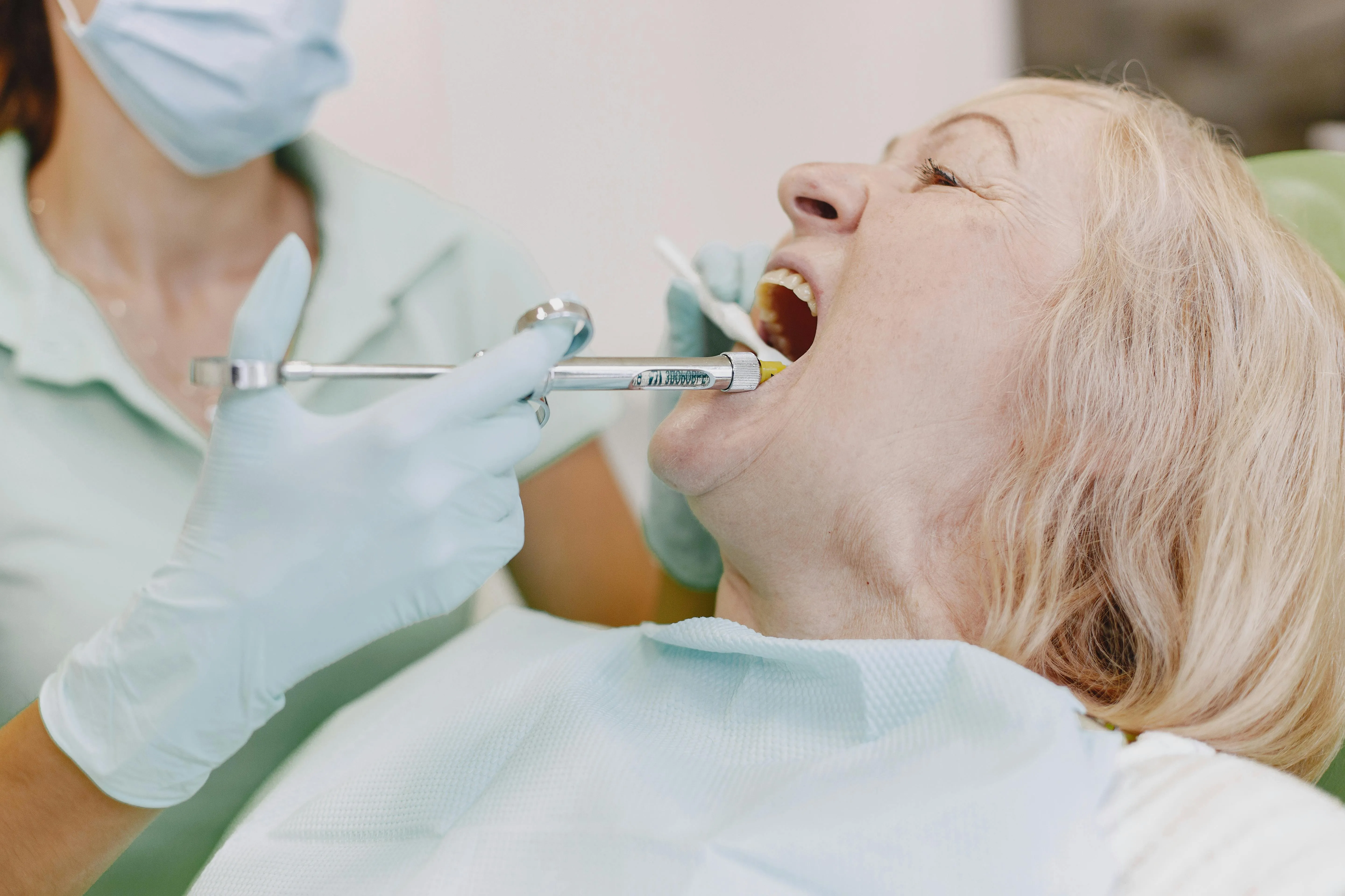 Dental tool delivering local anesthetic near a patient's open mouth to provide immediate pain relief during an emergency dental procedure