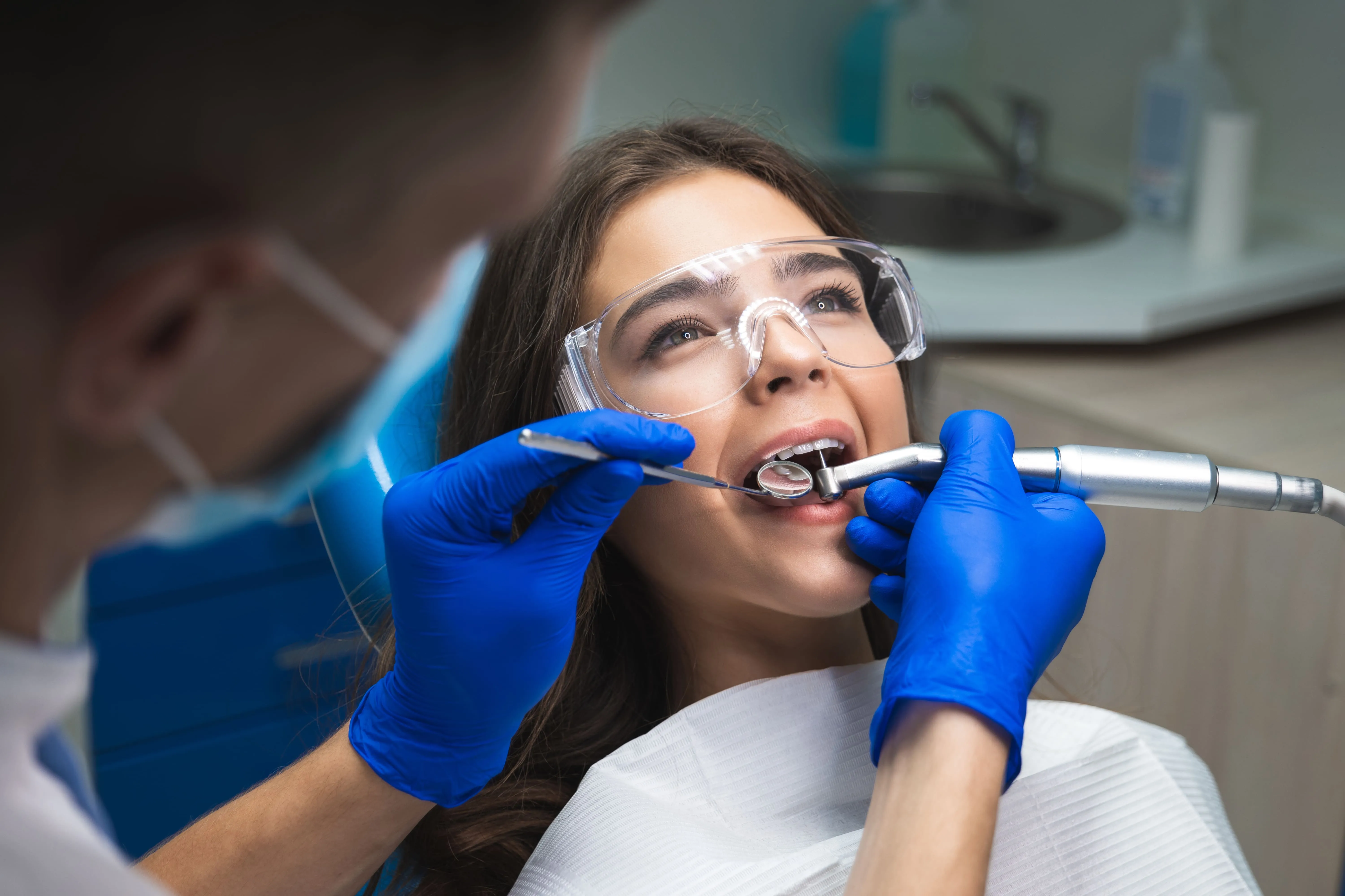 Patient wearing protective glasses reclined in a dental chair while a dental professional performs root canal therapy, representing comfortable, modern treatment at Ortega Cottage Dentistry