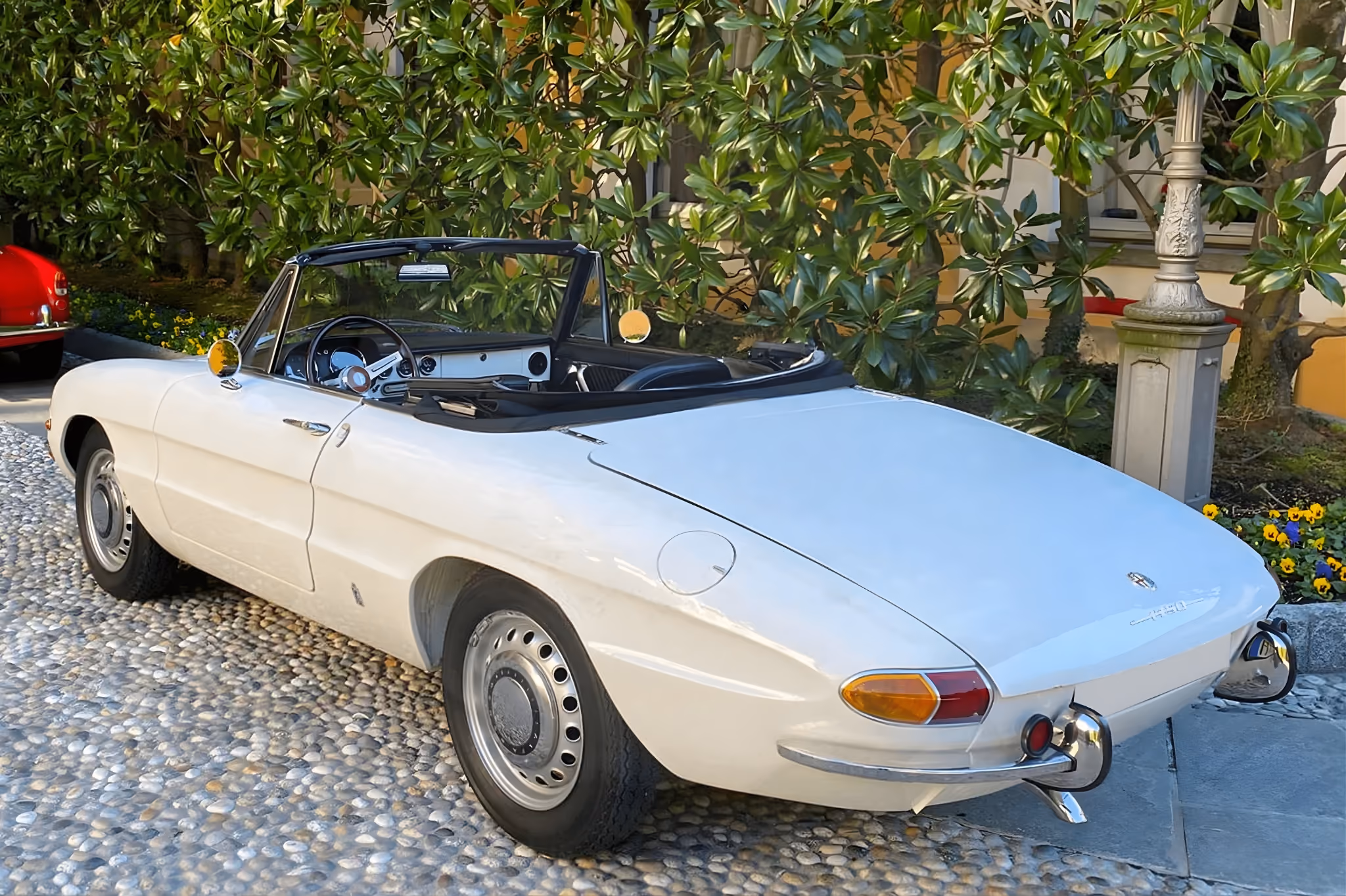 Rear exterior view of the white Alfa Romeo Spider Osso di Seppia convertible in an elegant setting