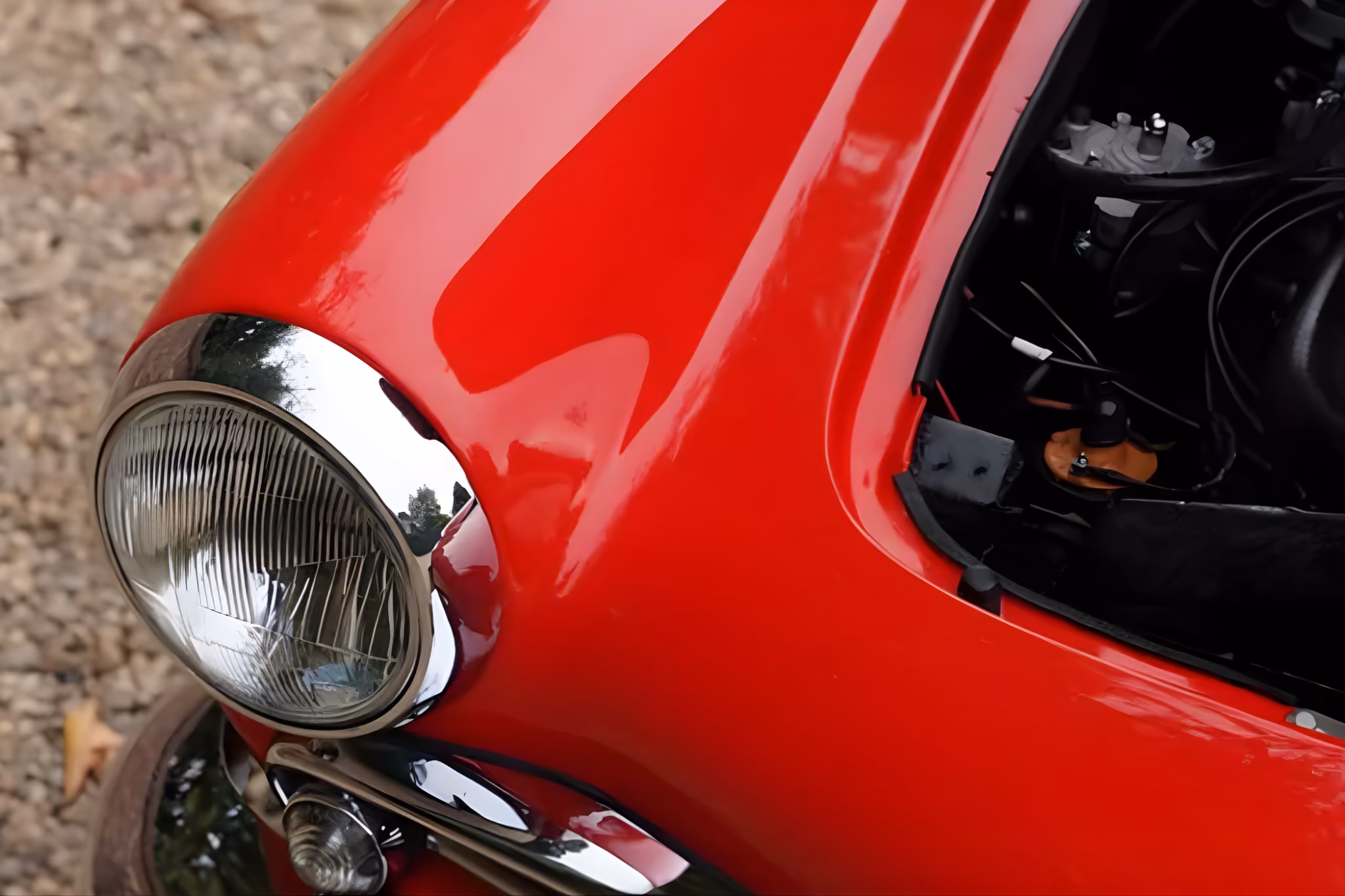 Close-up detail of the headlight and red bodywork of the Alfa Romeo Giulietta Spider