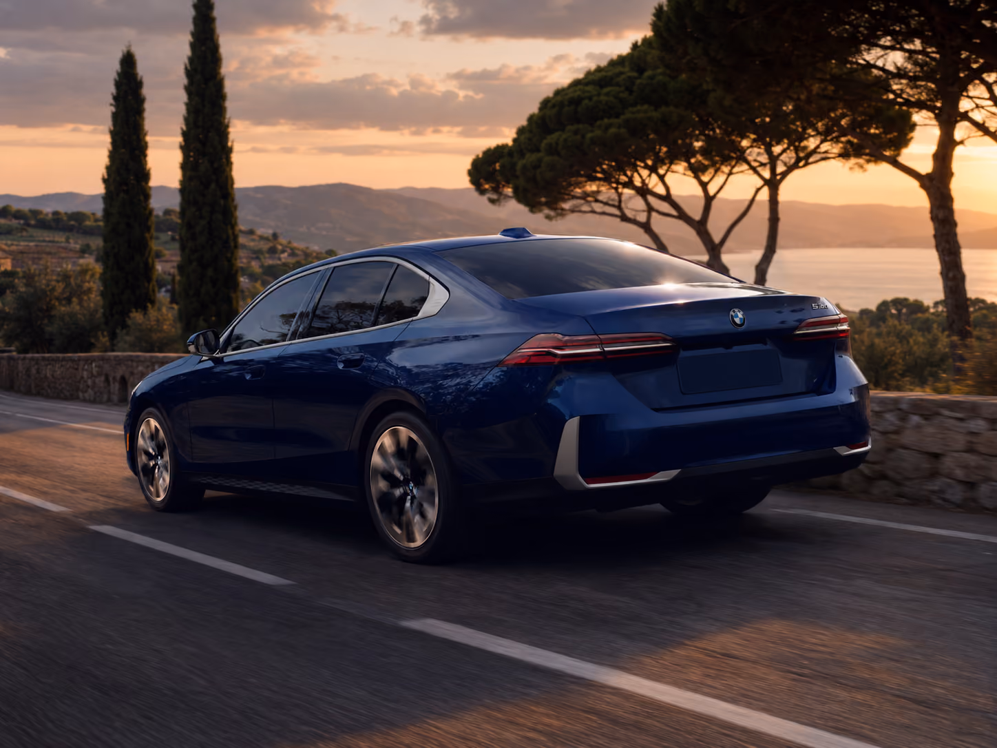 Rear side view of the BMW Executive Sedan driving at sunset for elegant self-drive rental