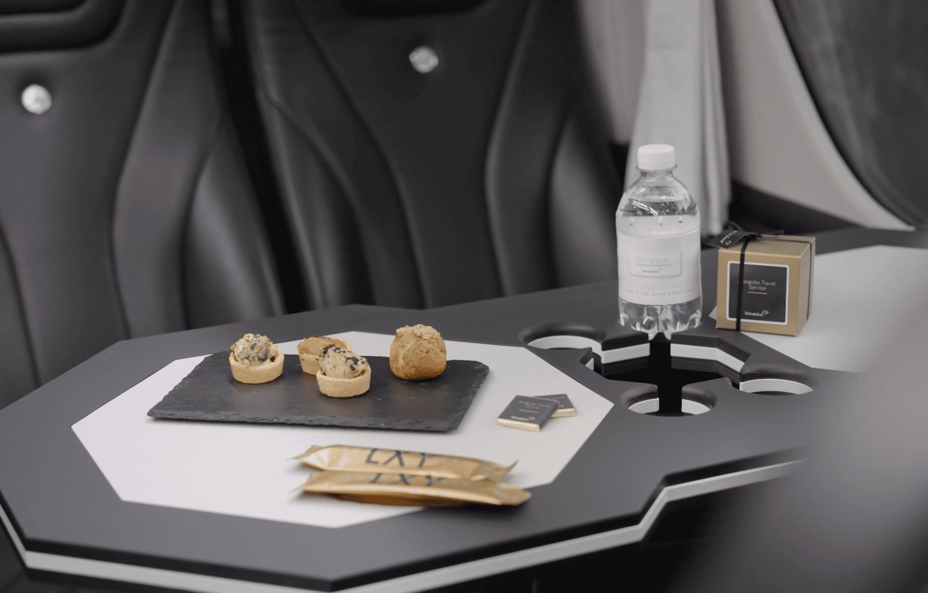 Aperitif table detail inside the Moveolux Luxury Minibus 16 with water and snacks