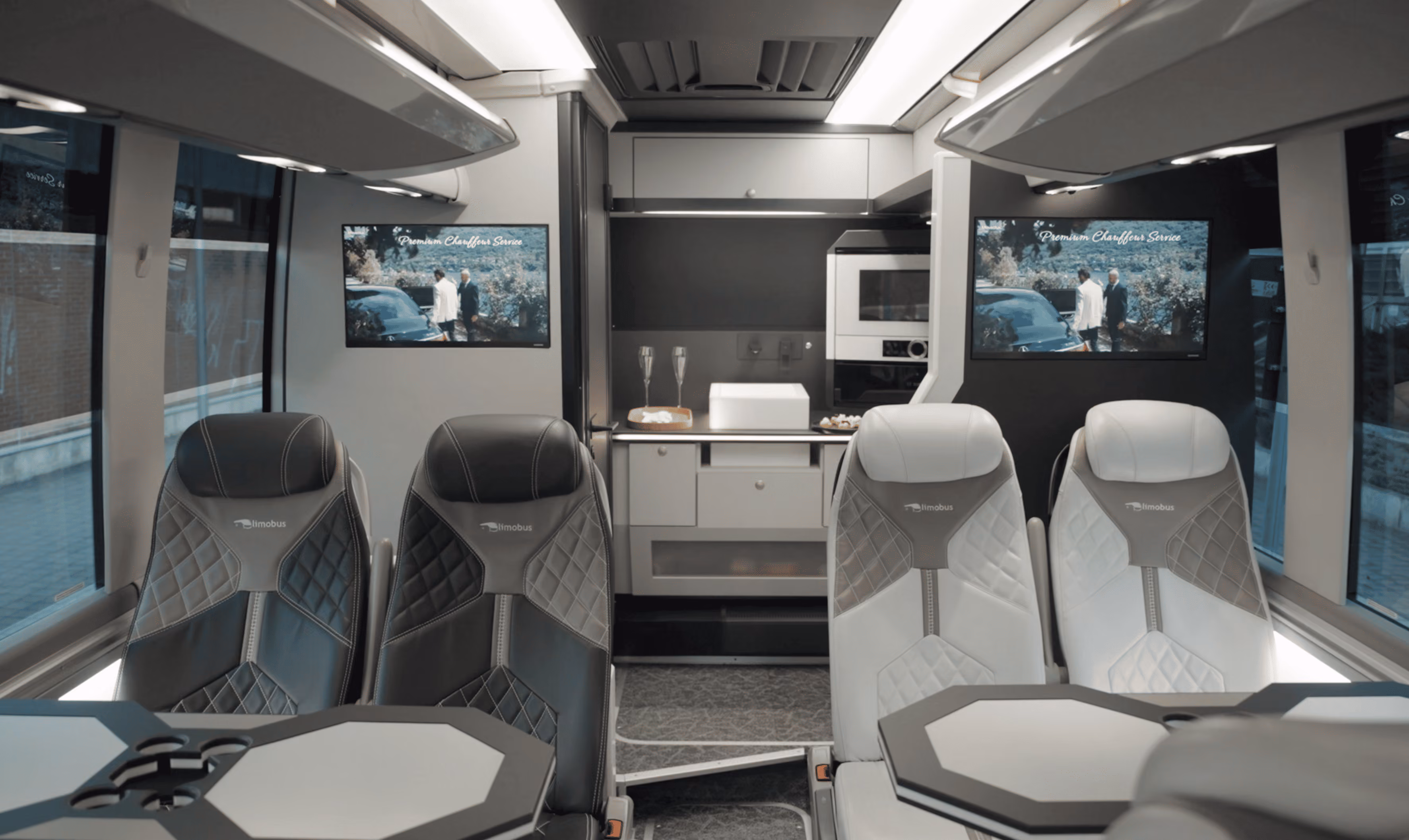Front lounge view inside the Moveolux Limobus Elements 20 with tables and onboard screens