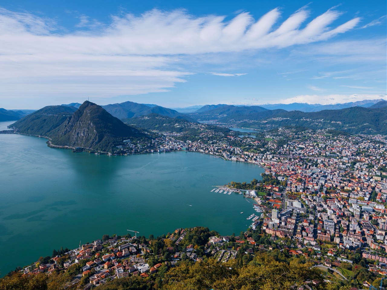 Aerial view of Lake Lugano and the city skyline, Moveolux luxury chauffeur service in Lugano