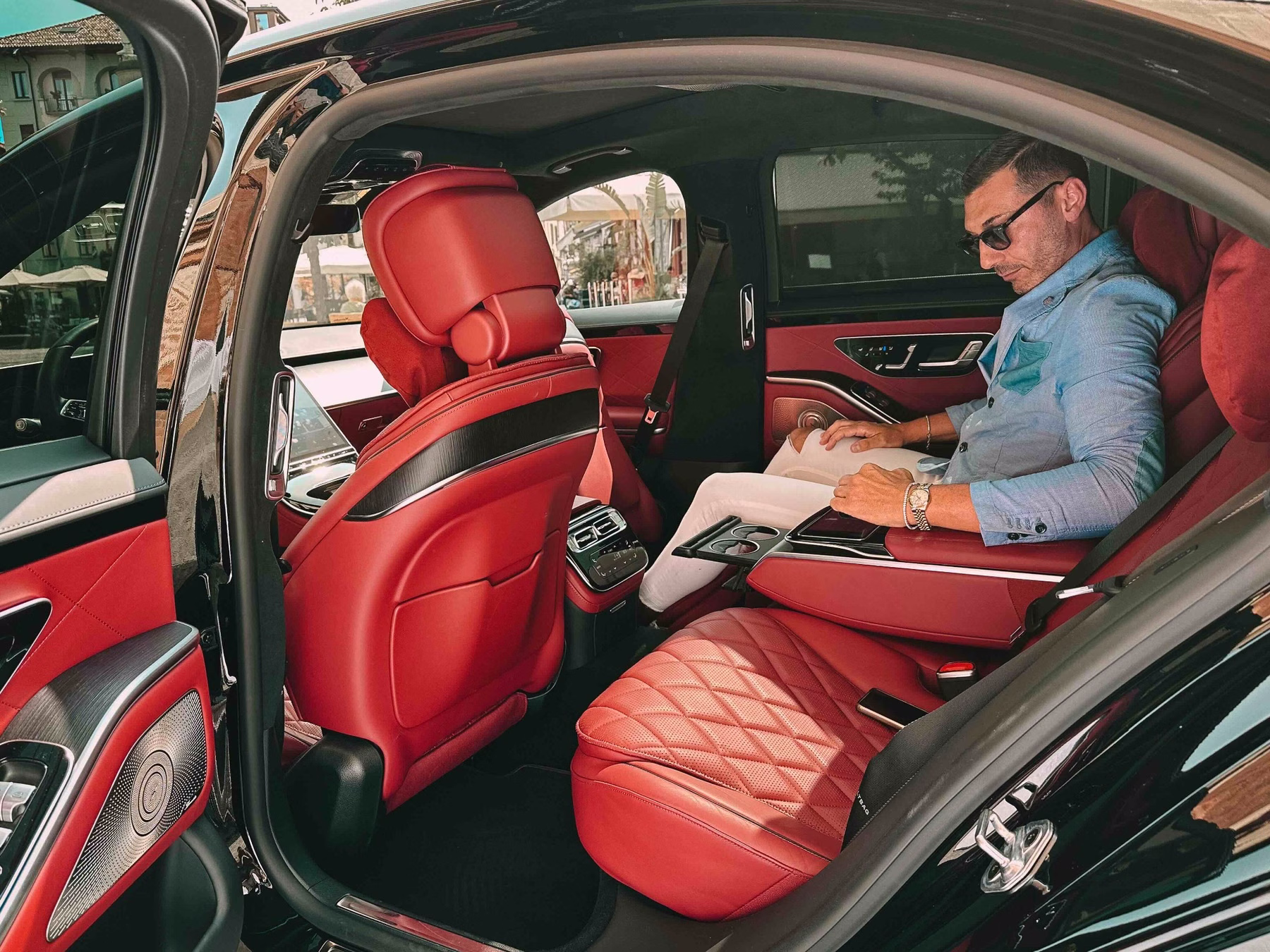 Interni di auto luxury con sedili posteriori in pelle rossa e passeggero business a bordo durante un servizio chauffeur Moveolux