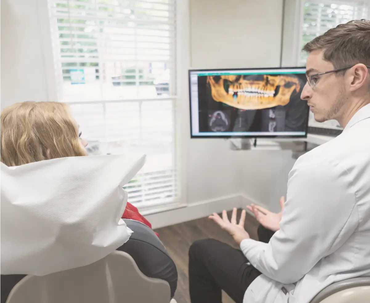 A dentist explains a dental X-ray to a patient seated in a dental office.