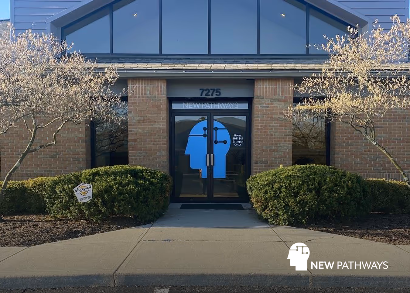 Exterior of a building with the New Pathways Ketamine Clinic logo spread across two glass doors. The New Pathways logo is in the bottom right corner.