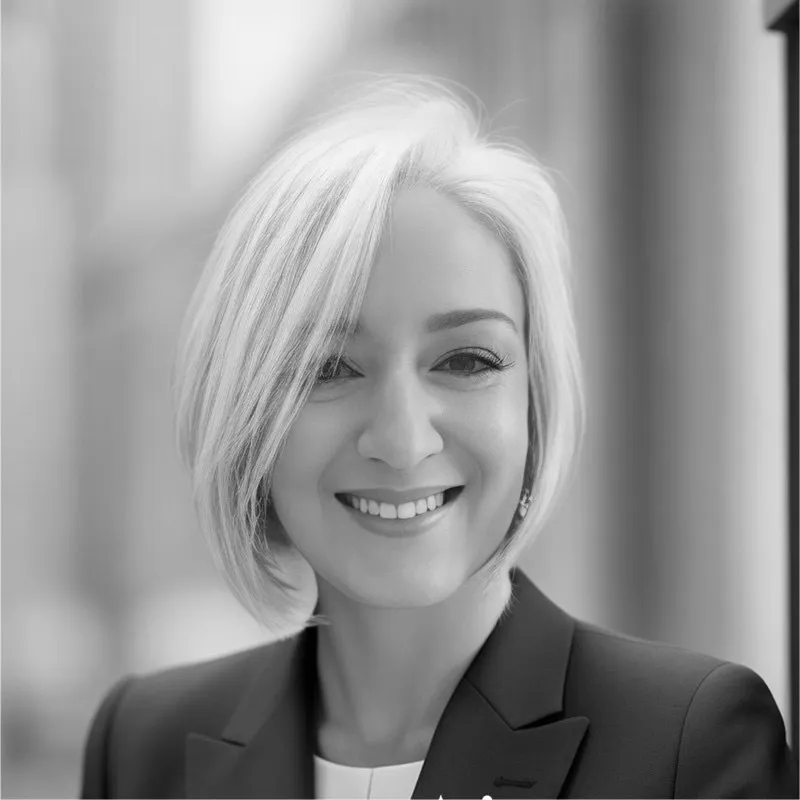 Black and white headshot of a smiling woman with short white hair wearing a dark blazer.