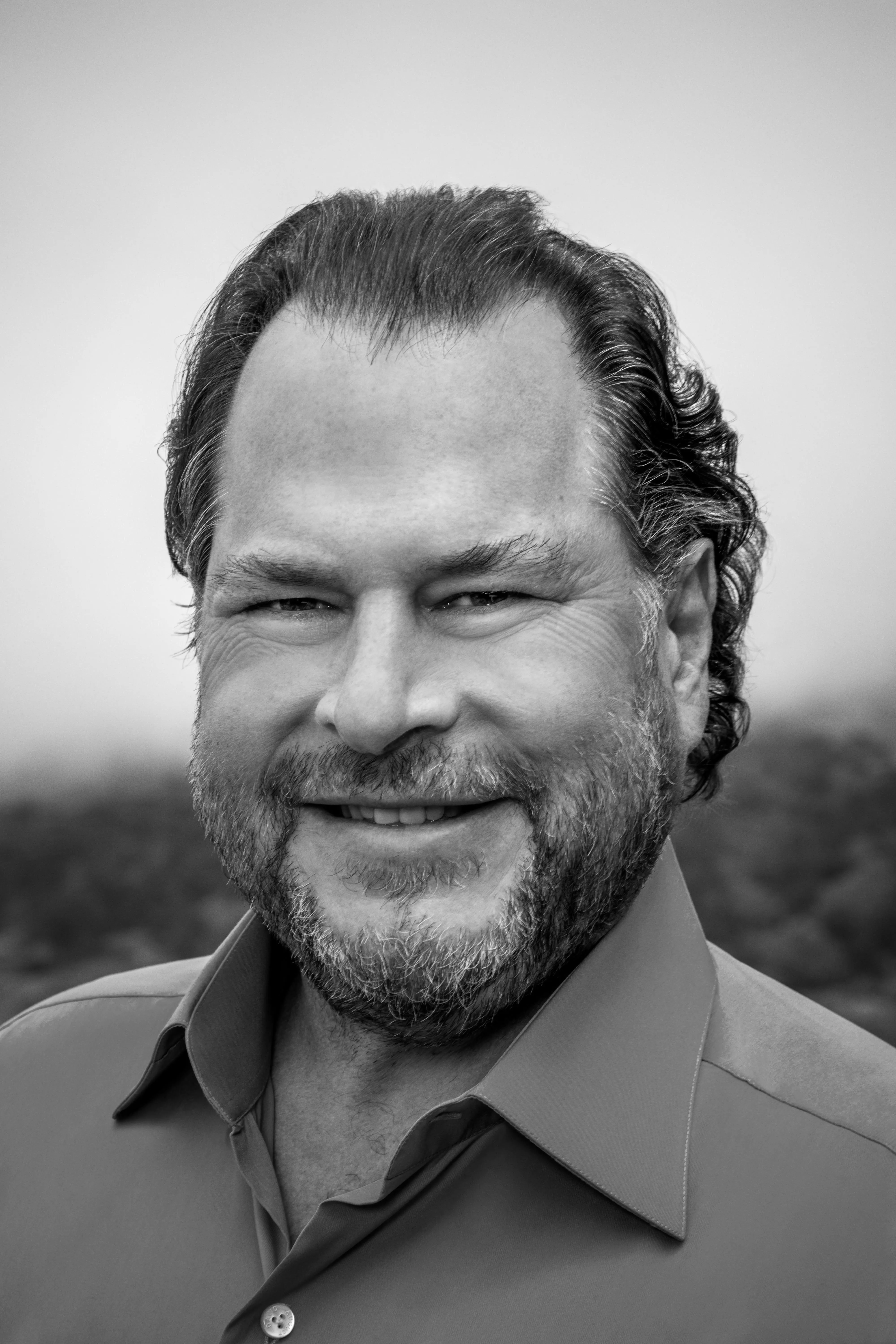 Black and white portrait of a smiling man with a beard wearing a collared shirt.