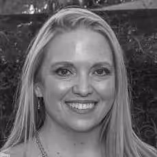 Black and white portrait of a smiling woman with long straight hair and earrings.