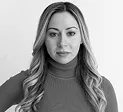 Black and white portrait of a woman with long wavy hair wearing a turtleneck sweater.