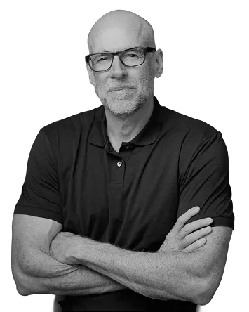 Middle-aged bald man with glasses and a beard, wearing a black polo shirt, standing with arms crossed.