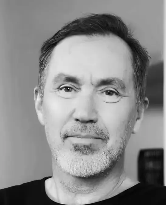 Black and white portrait of a middle-aged man with short dark hair and gray beard, wearing a dark shirt.